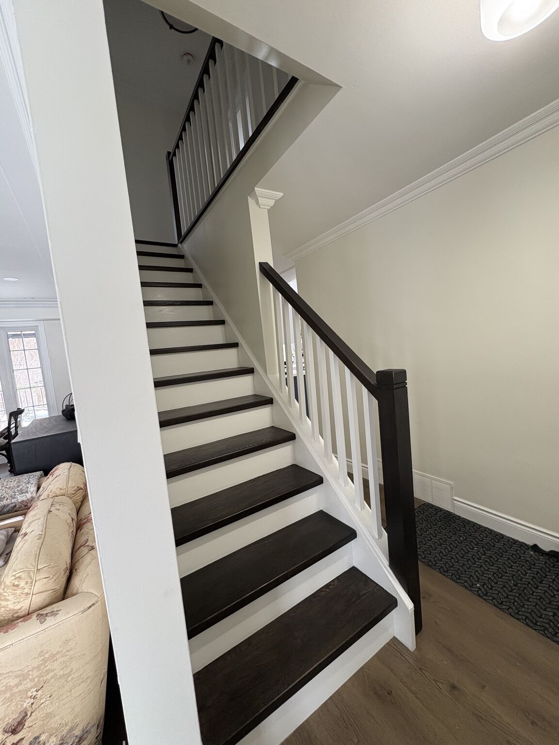 Finished staircase renovation by Bulldawgs Construction - dark stained treads with white spindle railing